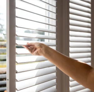 hand reaching out to adjust the louvres on shutters in Sussex