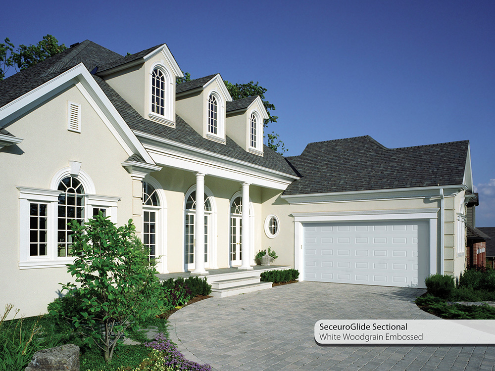 white house with grey roof and white seceuroglide sectional garage door